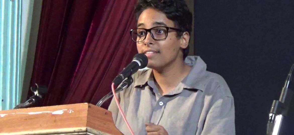 Dalit queer activist Bittu speaking into a mike at a podium.