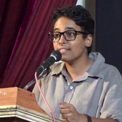 Dalit queer activist Bittu speaking into a mike at a podium.