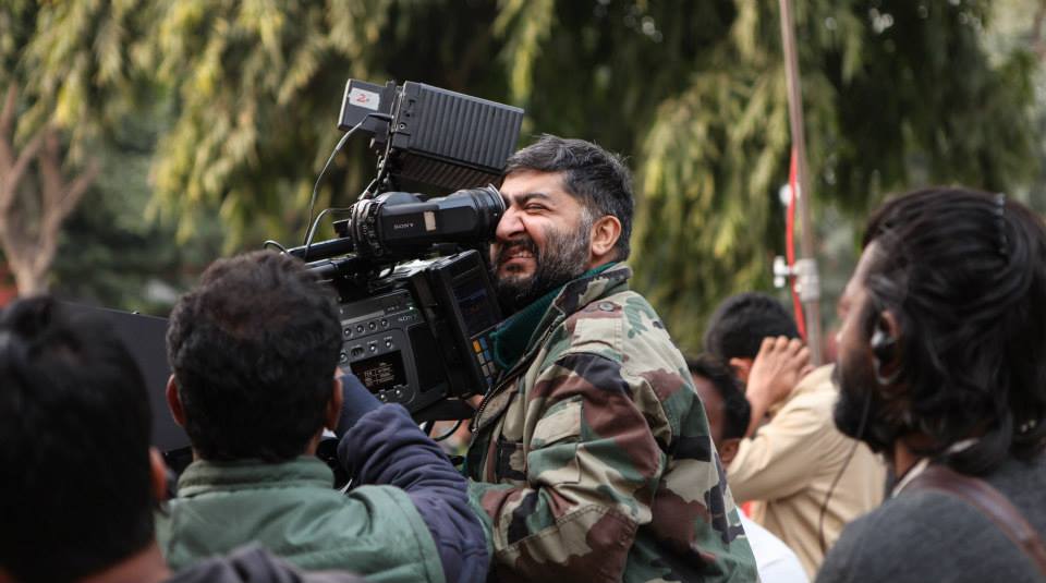 Photo of trans activist and cinematographer Satya Rai Nagpaul, holding up a camera to shoot a film