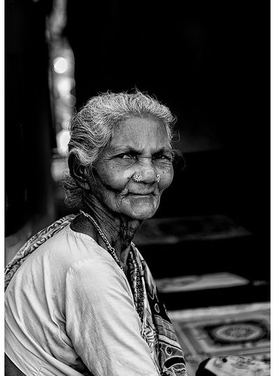 A black-and-white picture of an old woman who is staring directly into the camera.
