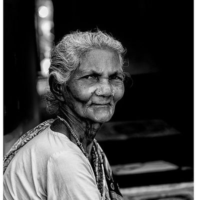 A black-and-white picture of an old woman who is staring directly into the camera.