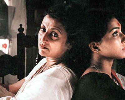 A still from ‘Paromitar Ek Din’, showing actors Rituparna Chatterjee and Aparna Sen leaning against each other.
