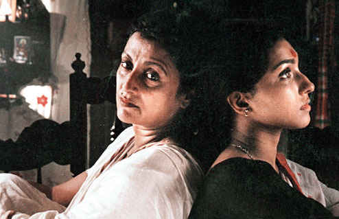 A still from ‘Paromitar Ek Din’, showing actors Rituparna Chatterjee and Aparna Sen leaning against each other.