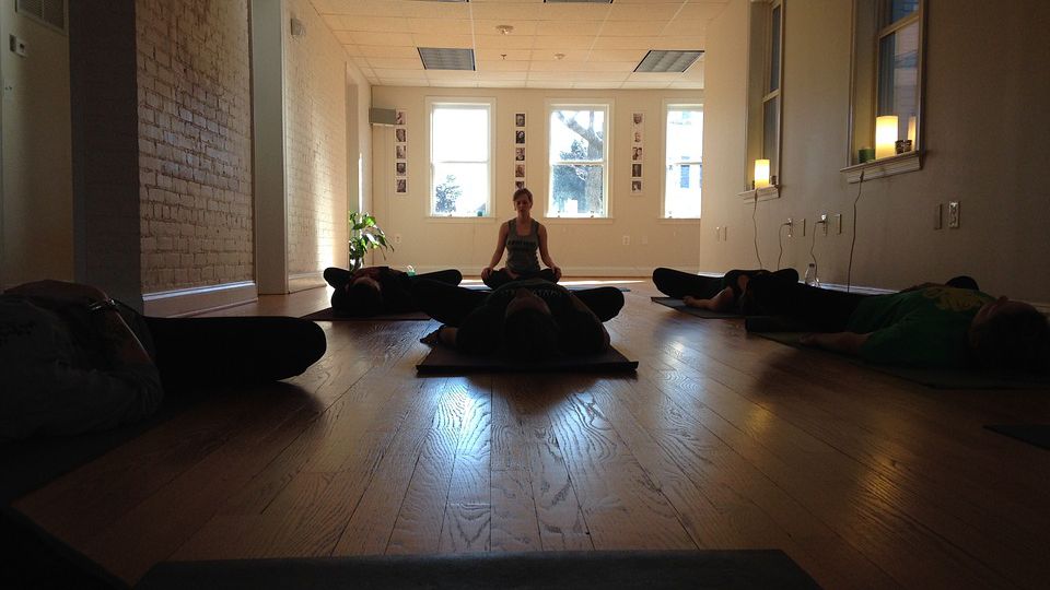 picture of a woman meditating in an empty room with dark brown interiors