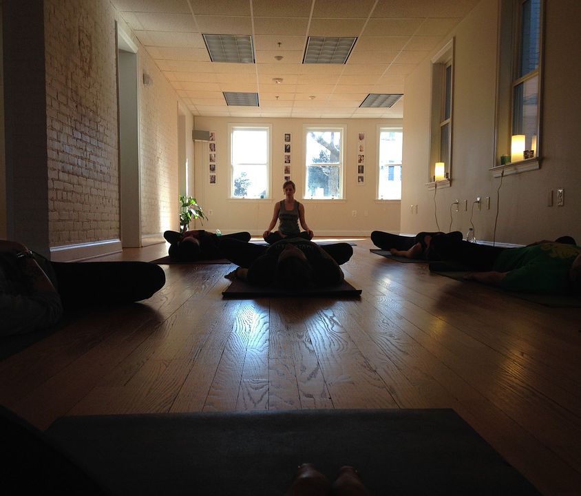 picture of a woman meditating in an empty room with dark brown interiors