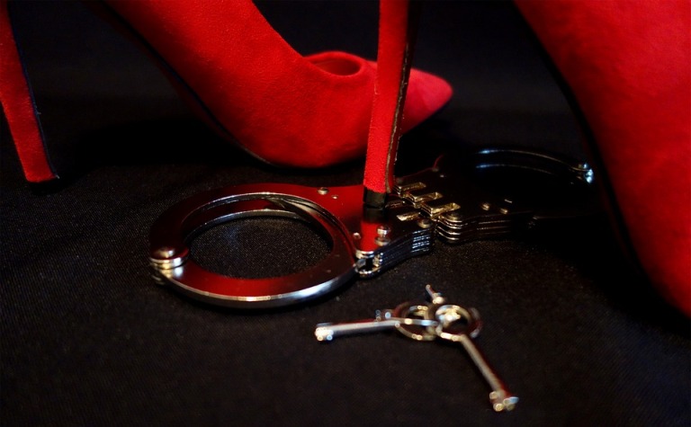 a picture of bdsm handcuffs lying on the floor with someone's foot wearing a heel beside it