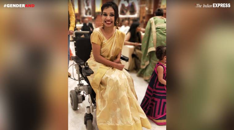 Picture of a woman in a wheelchair. Her hair is tied back in a bun and she is wearing a white saree and makeup.