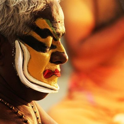 Picture of a classical dance performer, face painted in yellow and black