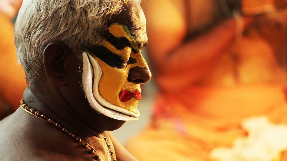 Picture of a classical dance performer, face painted in yellow and black