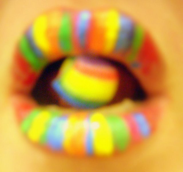 Picture of a woman's mouth, with her lips and tongue painted in rainbow colours