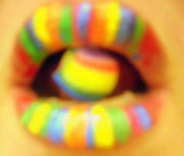 Picture of a woman's mouth, with her lips and tongue painted in rainbow colours