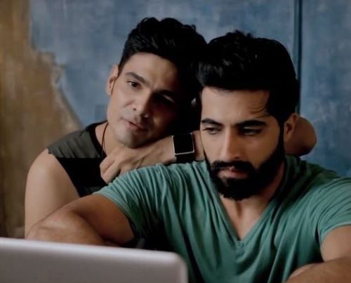 Screengrab from "Baby Steps", a gay couple sit together in front of a laptop in an intimate pose