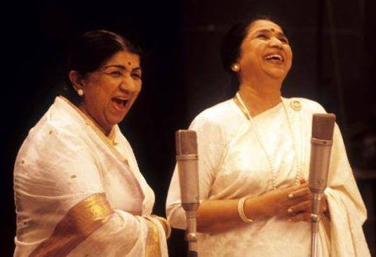 Picture of singers Lata Mangeshkar and Asha Bhonsale,. They are both dressed in sarees.