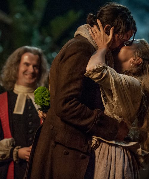 Picture of a man and woman, in period costume, kissing.