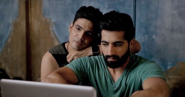 Screengrab from "Baby Steps", a gay couple sit together in front of a laptop in an intimate pose