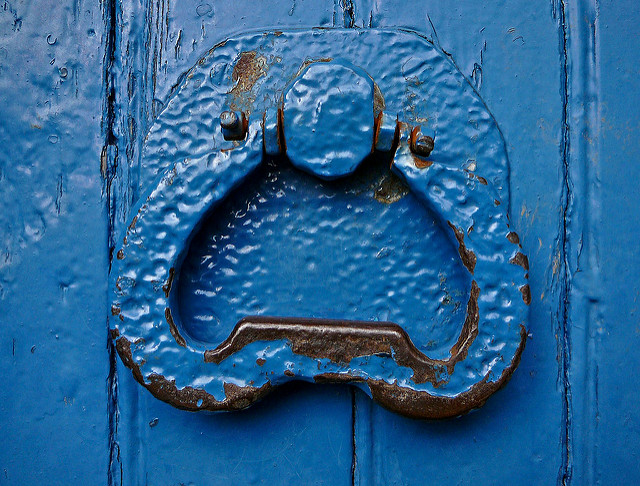 Picture of a wooden door and door knocker, painted bright blue