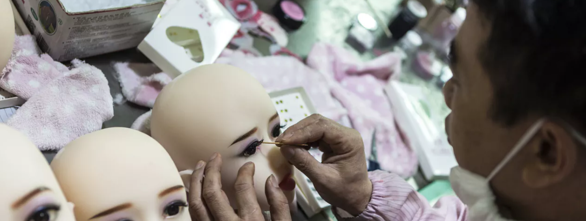 A pair of hands carress the head of a sex robot