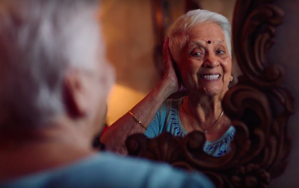a woman with grey hair looks into the mirror and smiles
