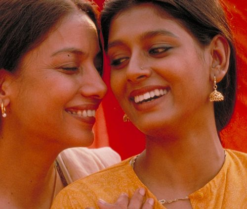 Still from "Fire", showing two women standing together intimately, smiles on their faces