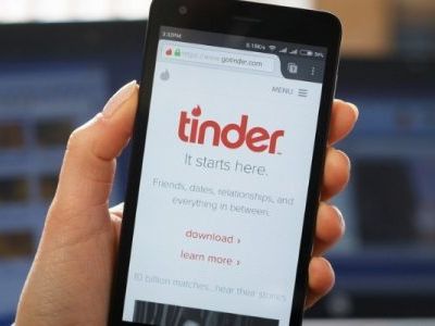 A hand holding up a phone where the tinder app is open