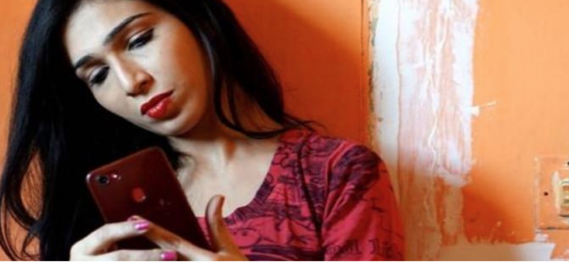 A woman with long dark hair stares into her phone, seemingly taking a selfie