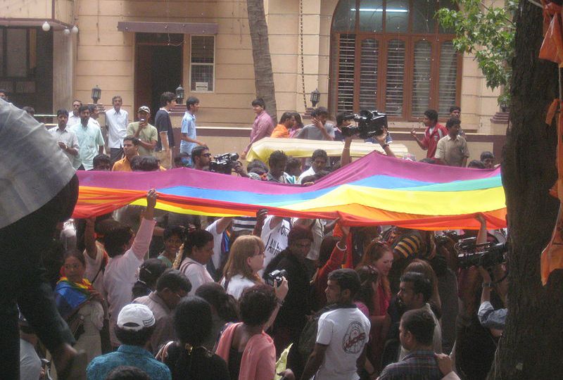 an image of a rainbow pride flag being carried by a large crowd