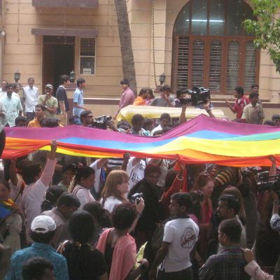 an image of a rainbow pride flag being carried by a large crowd