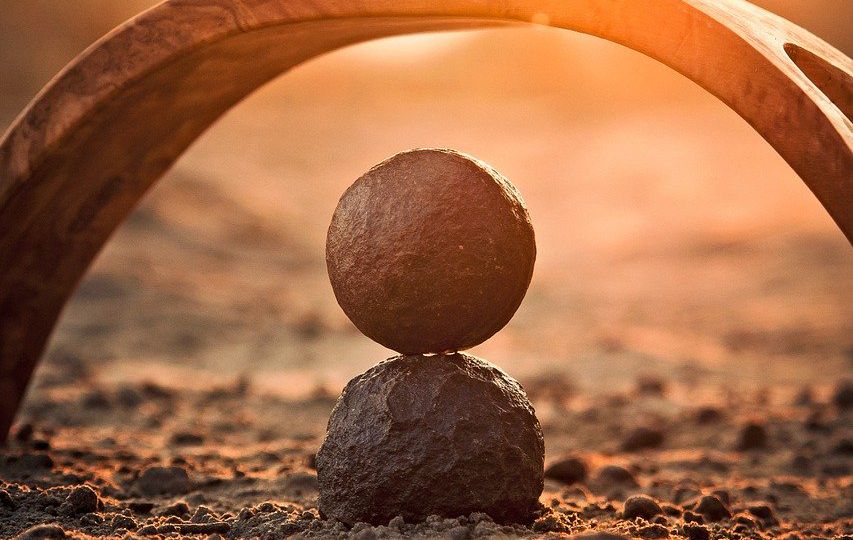 An image of a rocky, dusty terrain with two semi-circular stone structures with spherical rocks in the middle.