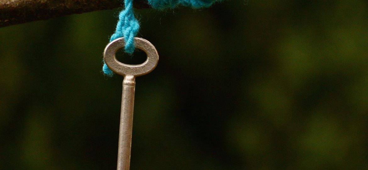 A key hanging off blue thread draped around a branch