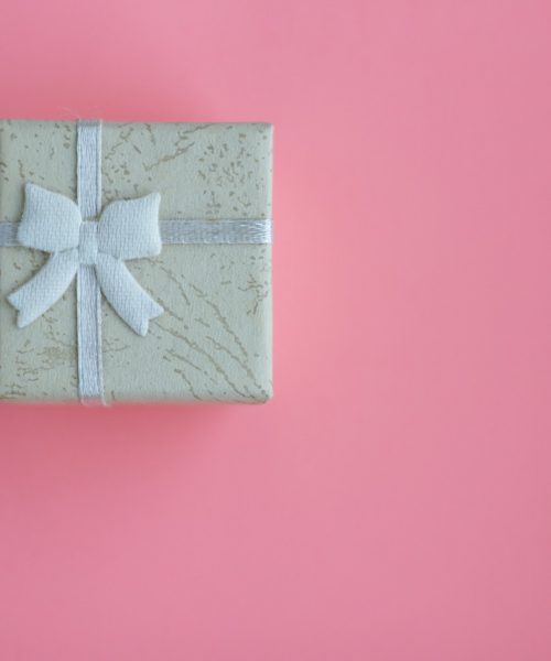 On a pink background, a blue gift-wrapped box with a bow