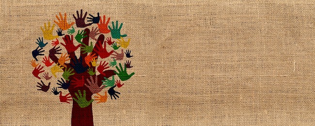 On a jute-textured background, hand-prints in different colours form the leaves of a tree, the trunk and branches of which are a hand-print.