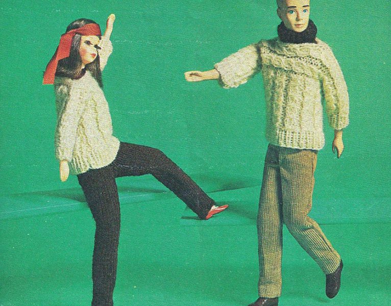 Image of two dolls swaying their legs and arms. The doll on the left has long hair and is wearing a red coloured head scarf on its head and a white sweater and black pants. The doll also has makeup on its face. The doll on the rights has short hair and is wearing a white sweater with grey pants. The doll has a black woolen scarf around its neck