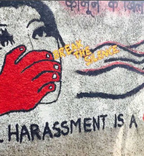 एक महिला के मुँह को ढक रहे एक लाल रंग के हाथ का भित्ति चित्र। चित्र के साथ पीले रंग में सन्देश है: 'चुप्पी तोड़ों', उसके नीचे बड़े अक्षरों में लिखा है: 'यौन उत्पीड़न एक अपराध है' और उसके ऊपर: 'कानून के ख़िलाफ़'।