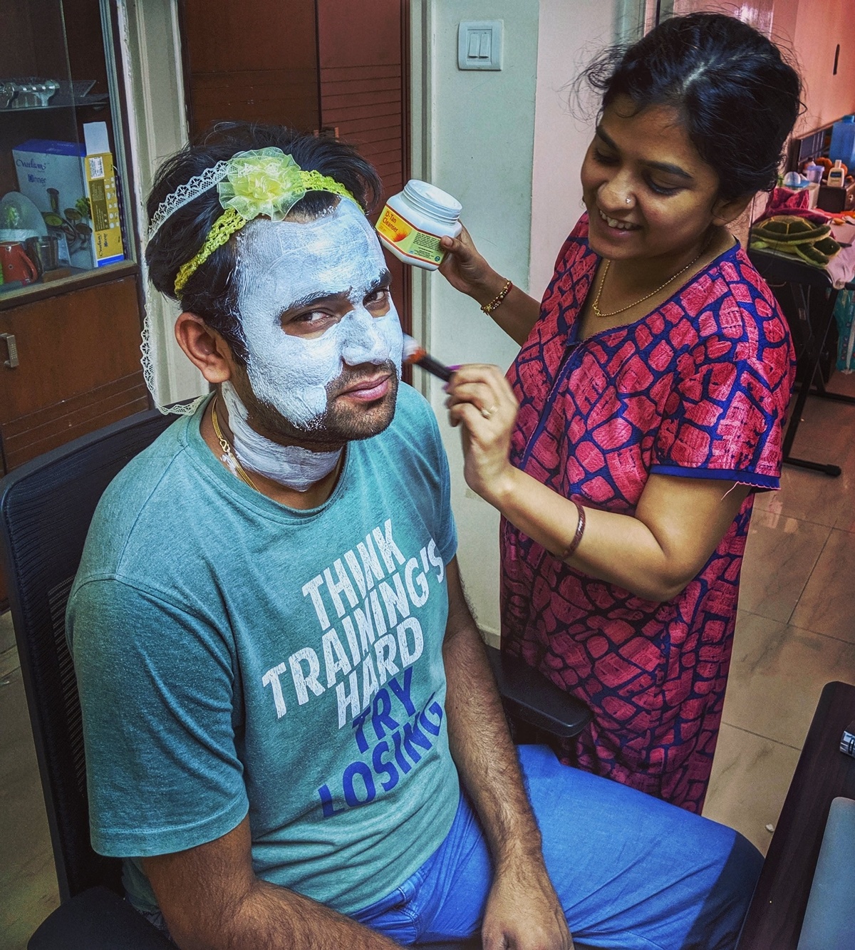 Women At Leisure: Sneha, helping her partner, Sourabh, put on a face mask. She put on their daughter’s hair bands on his head to prevent his hair from falling on his face.