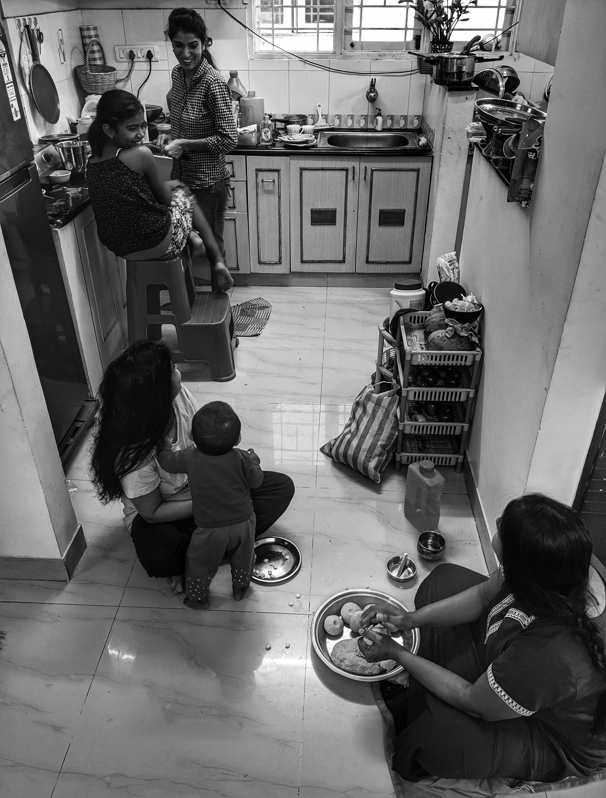 Women at Leisure: Girls and women in a family gathered in the kitchen to talk and also prepare an elaborate meal for rest of the family during a family reunion.