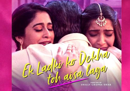 Poster of Bollywood movie ‘Ek Ladki ko Dekha toh aisa laga..’ Two women in traditional Indian attire are hugging a man in a white suit. The women are facing the front, while only the back of the man can be seen. The title of the movie “Ek Ladki ko Dekha toh aisa laga” is written in the bottom center, followed by text that reads “Directed by Shelly Chopra Dhar.”