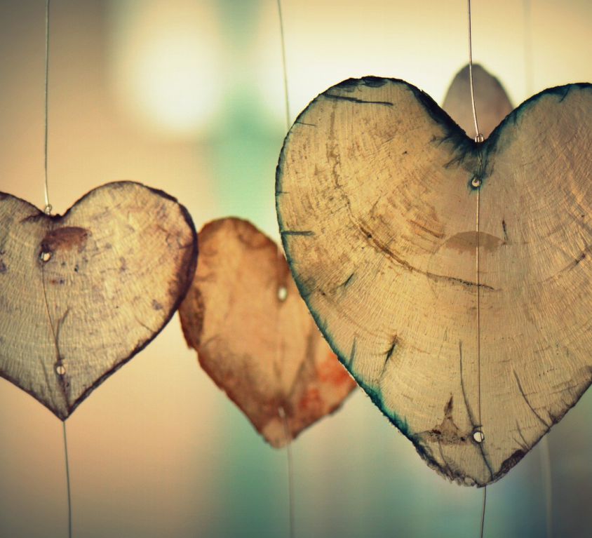 An illustration which depicts three heart-shaped pieces of wood suspended from wires, one of them clearly in the foreground, the other two a little smaller and in the background