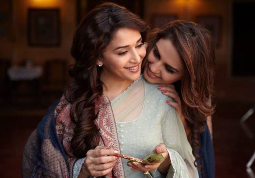 A shot from the film featuring the two female leads, one is preparing a paan with the other’s face resting on her shoulder. Both the women are smiling.