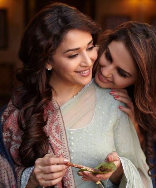 A shot from the film featuring the two female leads, one is preparing a paan with the other’s face resting on her shoulder. Both the women are smiling.