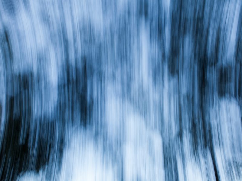 An abstract photo of blurred blue and white vertical lines that are spanning outwards