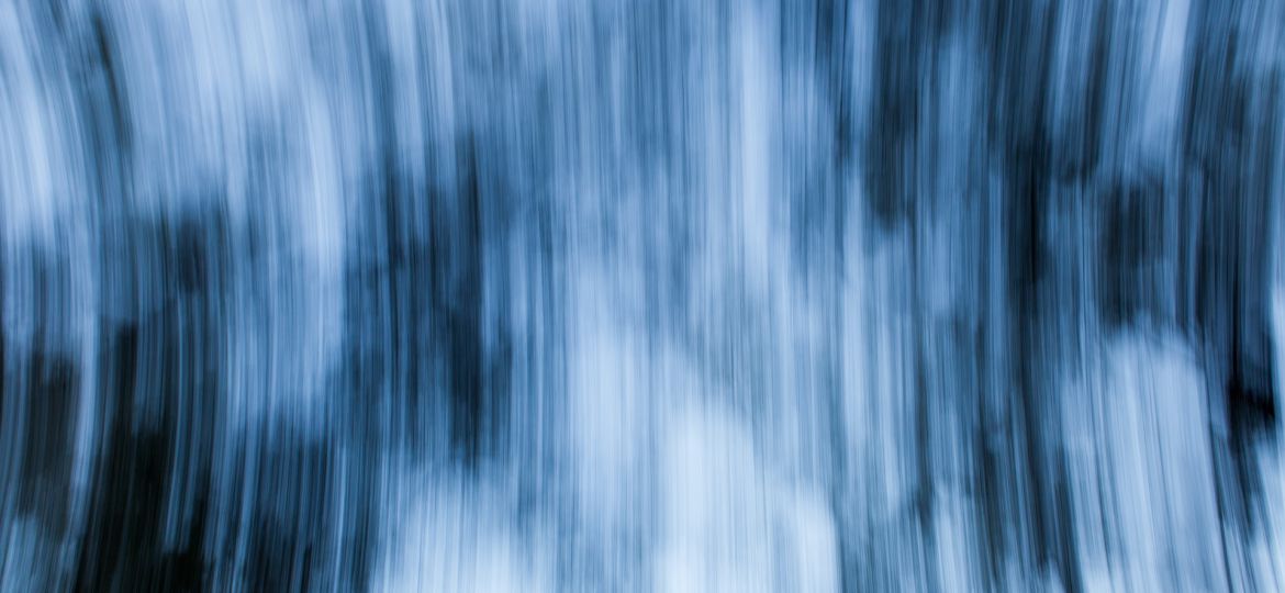 An abstract photo of blurred blue and white vertical lines that are spanning outwards