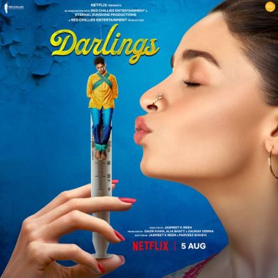 A poster of the movie Darlings. Alia Bhatt is blowing a kiss to a miniature Vijay Varma who is depicted hanging on the top of a syringe.