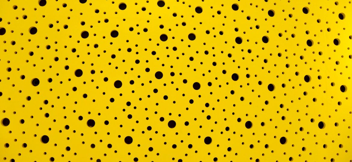 Black polka dots of different sizes against a yellow background.