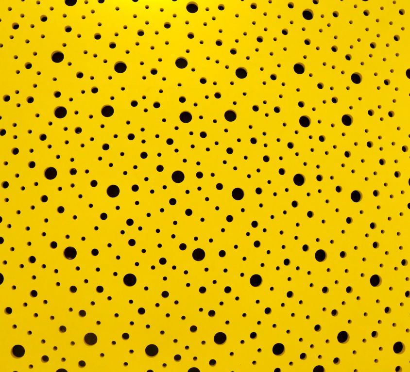 Black polka dots of different sizes against a yellow background.