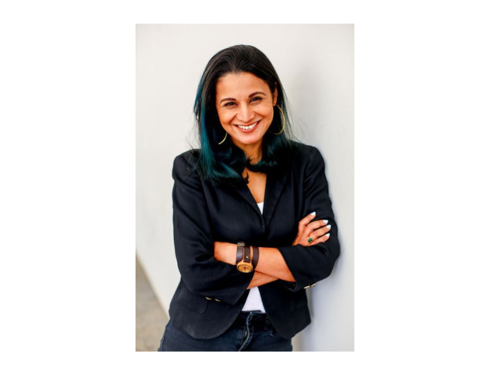 photograph of Prof Srila Roy leaning against a wall with her hands folded