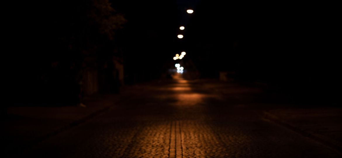 A dark path lit subtly by street lights