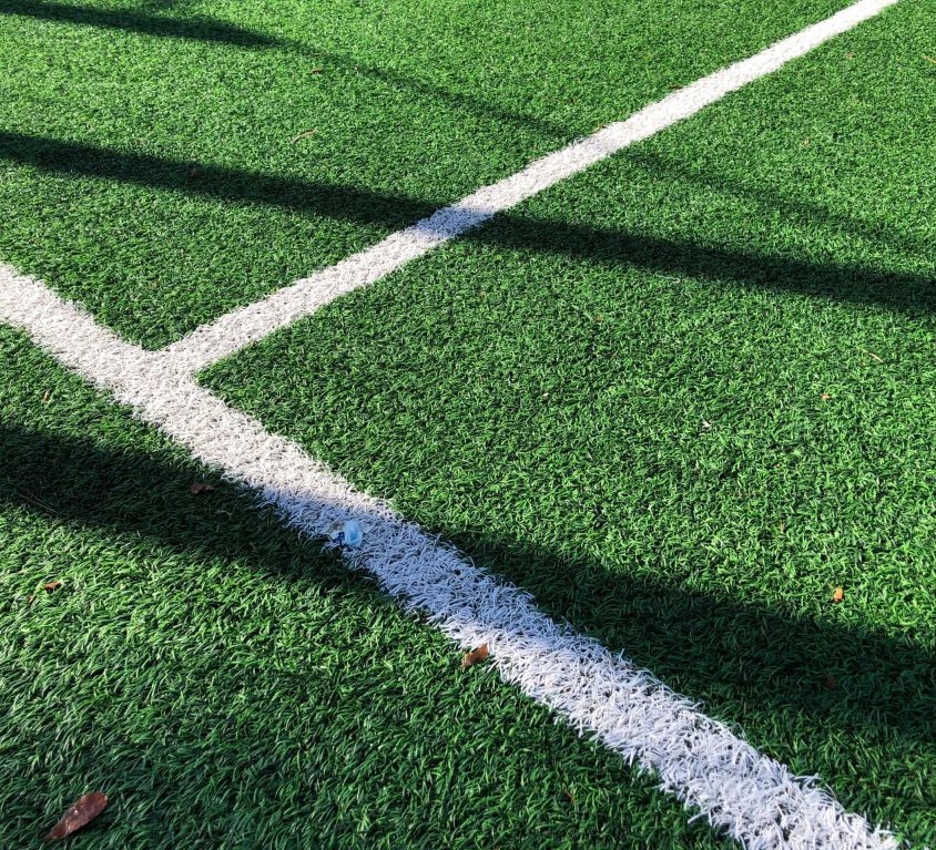 A close-up of a green playing field with dividing lines.