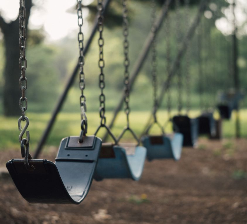 Selective focus shot of outdoor playground swings.