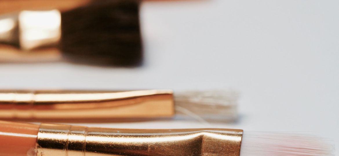 Close up photo of makeup brushes with gold metallic bodies and white hair.