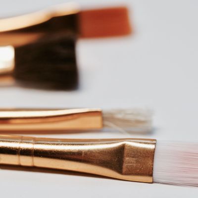 Close up photo of makeup brushes with gold metallic bodies and white hair.